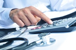 nito500150500007.jpg - closeup of a young caucasian healthcare professional wearing a white coat calculates on an electronic calculator