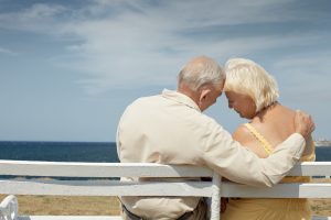 diego - senior caucasian couple sitting on bench near the sea and hugging. horizontal shape, rear view, copy space