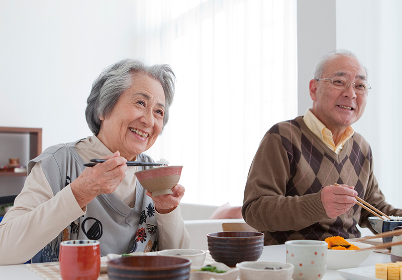 高齢の夫婦が笑顔で食事をしている様子