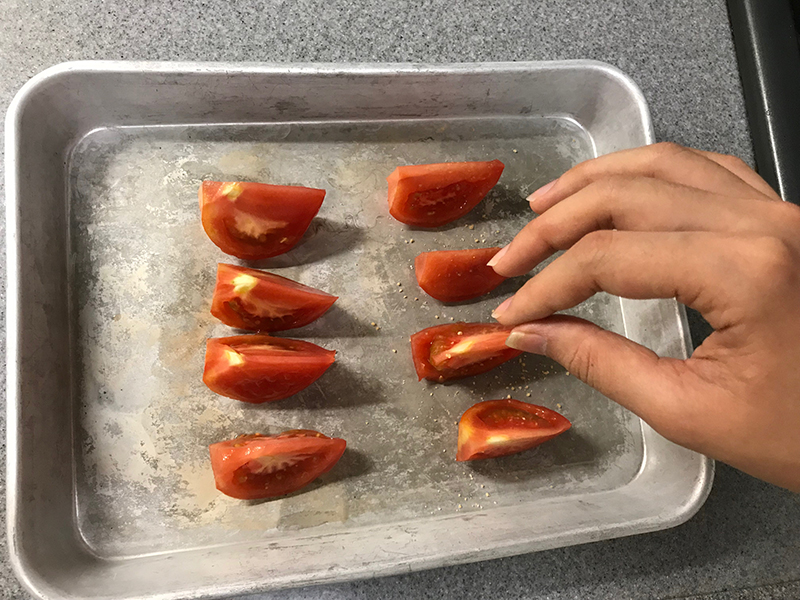 バットに並べたトマトに砂糖をかけている画像