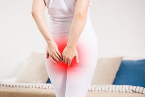 staras180800077.jpg - woman suffering from hemorrhoids at home, anal pain, painful area highlighted in red