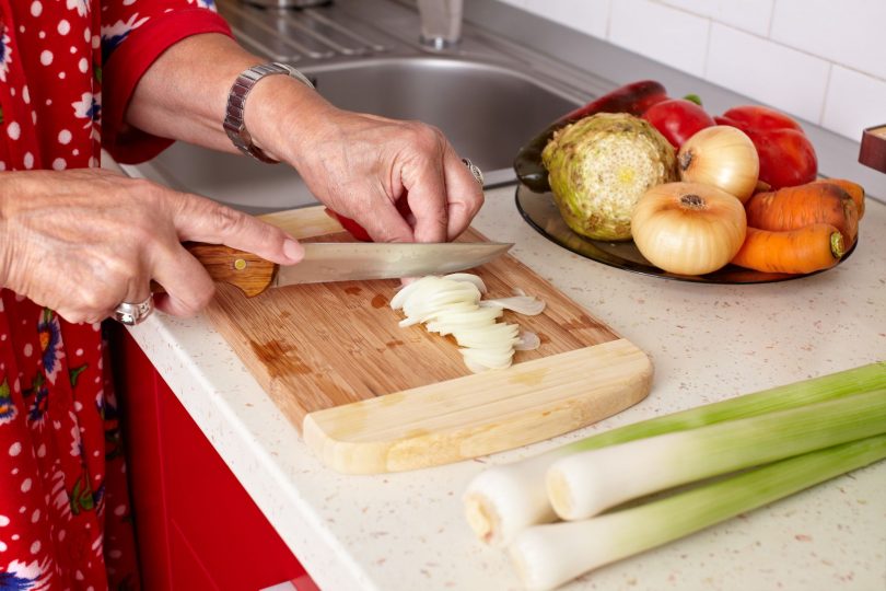 xalanx111000112.jpg - senior woman hands chopping vegetables on a wooden board in the kitchen