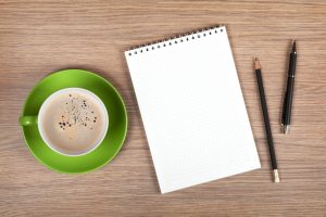 Blank notepad and coffee cup on office wooden table