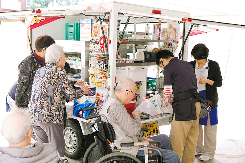 移動販売車で買い物をする老人と対応する店員