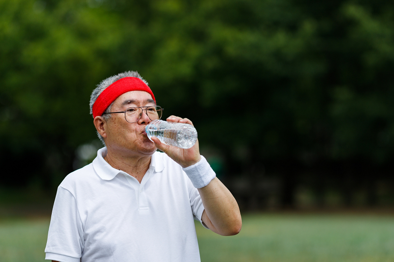 ペットボトルの水を飲む高齢男性