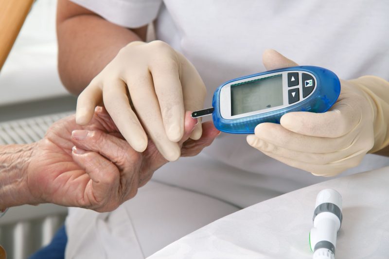 血糖値を計る検査をしている看護師と患者の手