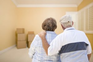 Hugging Senior Couple In Room Looking at Moving Boxes on the Floor.