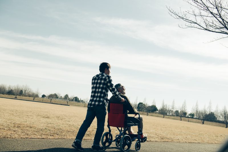車椅子の高齢者と若い男性