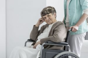 Worried senior lady sitting with blanket in wheelchair