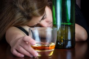 Drunk woman suffering from a hangover and holding a glass of liquor
