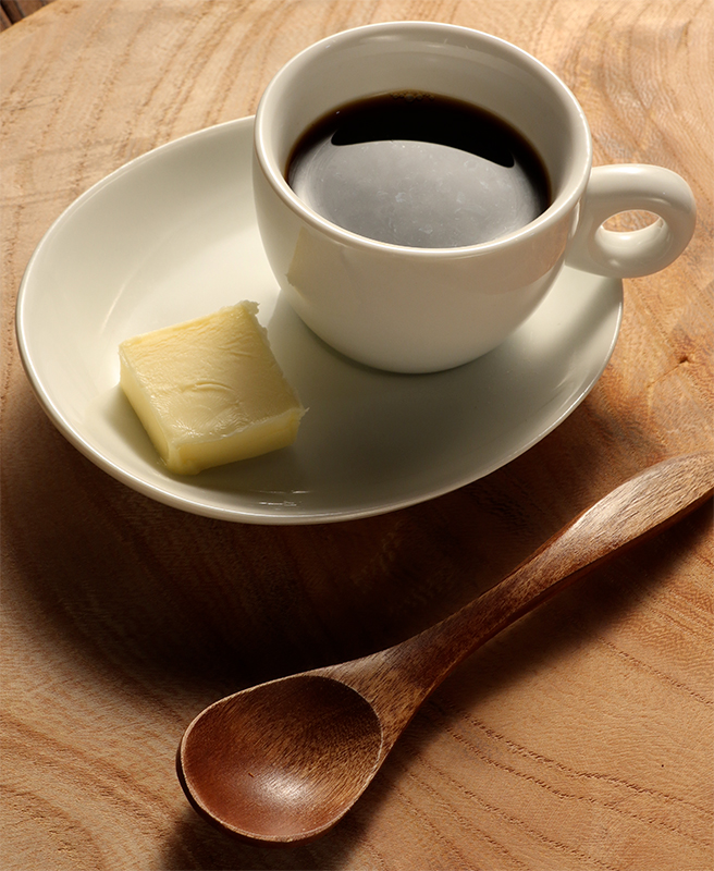 コーヒーとソーサーにのったバターがテーブルに置かれている