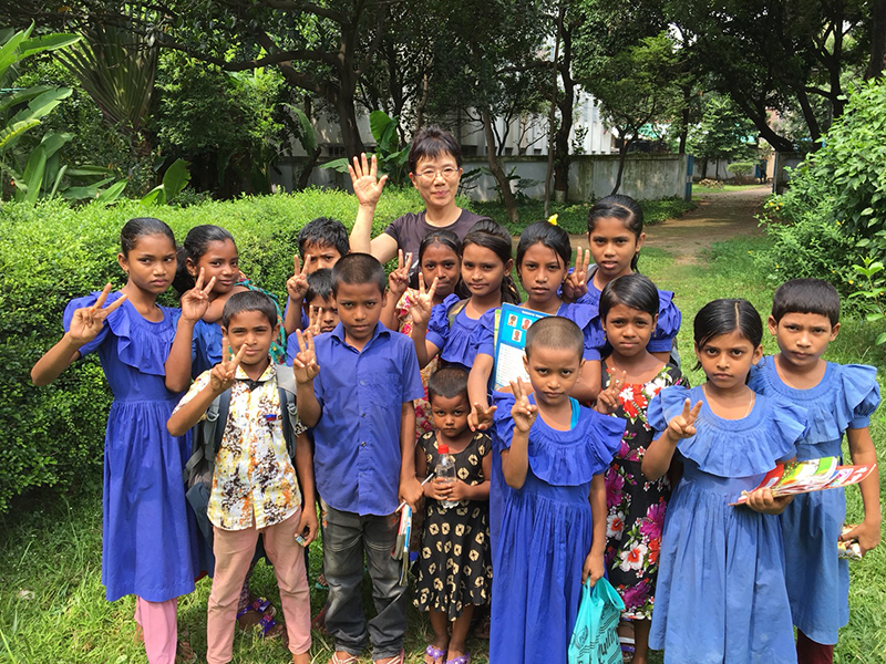 バングラデシュの小学校で子供たちと一緒に写真に写る鶴澤さん