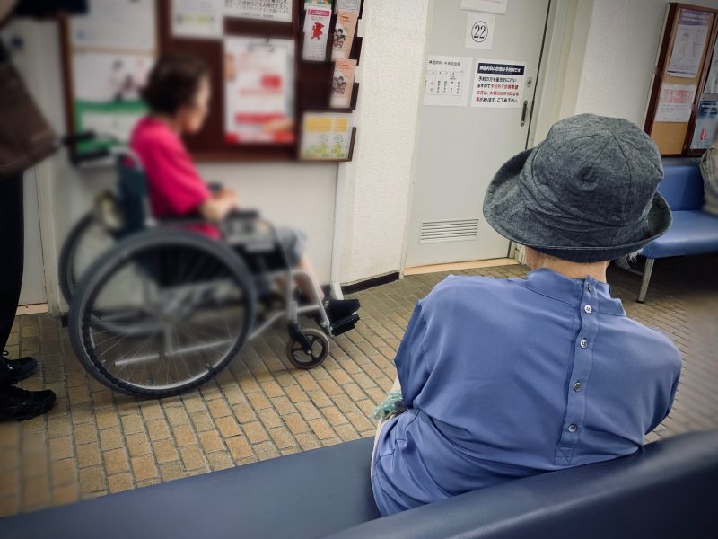 病院の待合室の椅子に座る母
