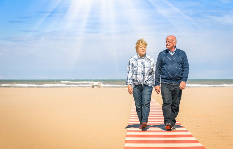 海辺を歩く高齢者カップル