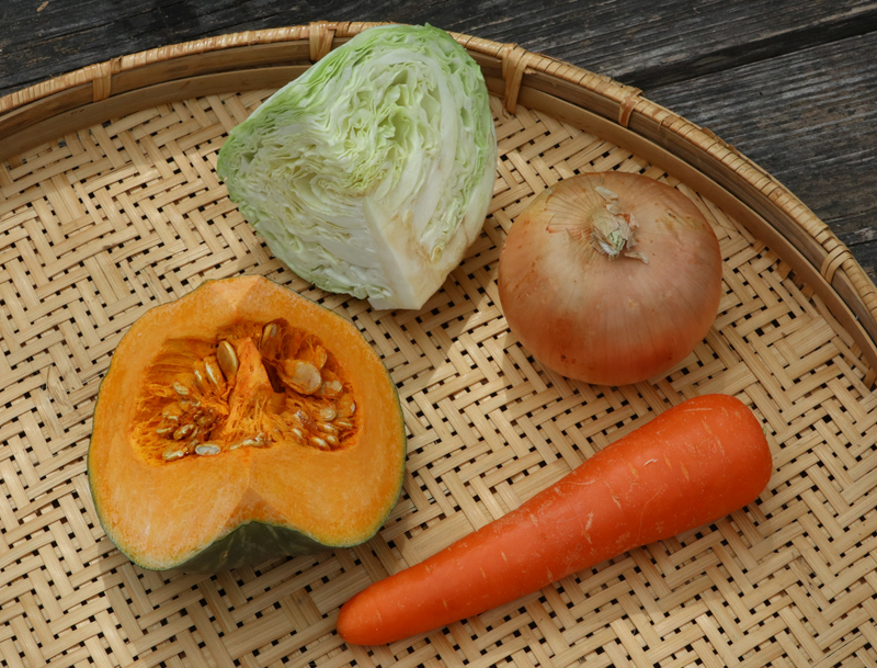 キャベツ、たまねぎ、にんじん、かぼちゃの４種類の野菜がザルにのっている