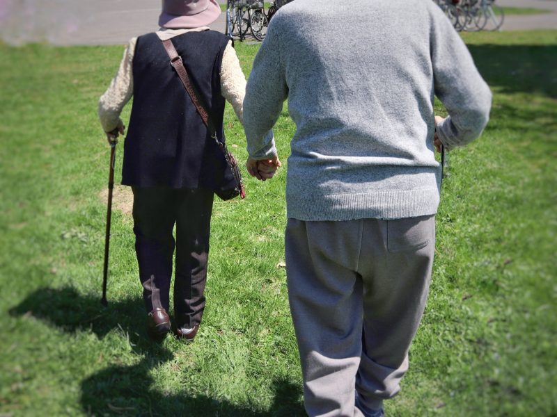 手を繋いで歩く高齢者の男女