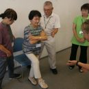 手を組んで片足を上げるシニアの写真