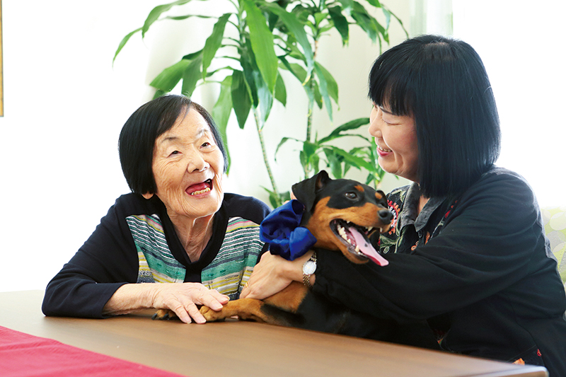 米田さん母娘が笑顔で愛犬と遊んでいる