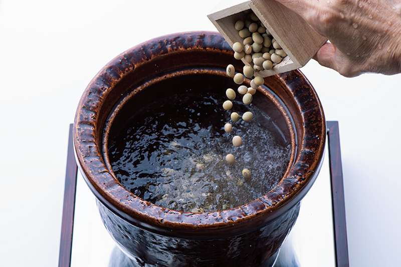 大き目の鍋に湯を沸かして、大豆を入れている