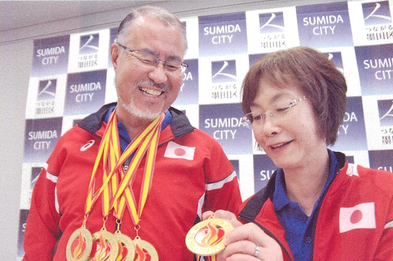 メダルを下げて笑顔を見せる世界移植者スポーツ大会の金メダリスト・若松力さんと妻の恵子さん