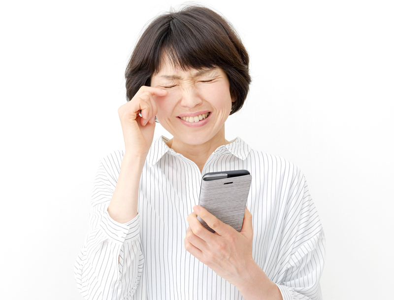 スマホを片手に泣く女性