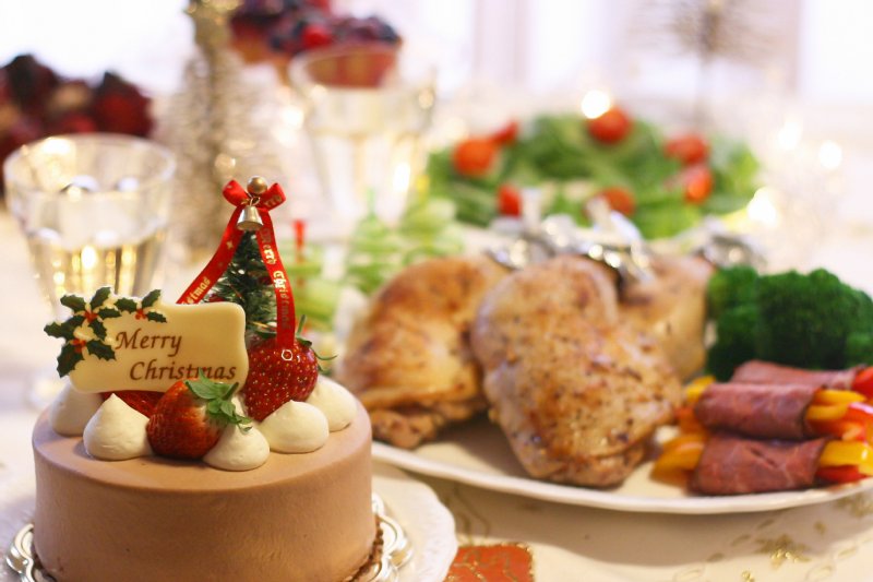 クリスマスケーキやチキンなど料理が乗ったテーブルの画像