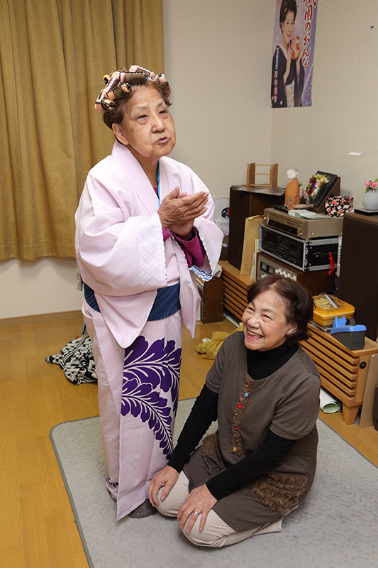 着物の丈を直してもらう幸子さんと、作業しながら笑顔の千秋さん