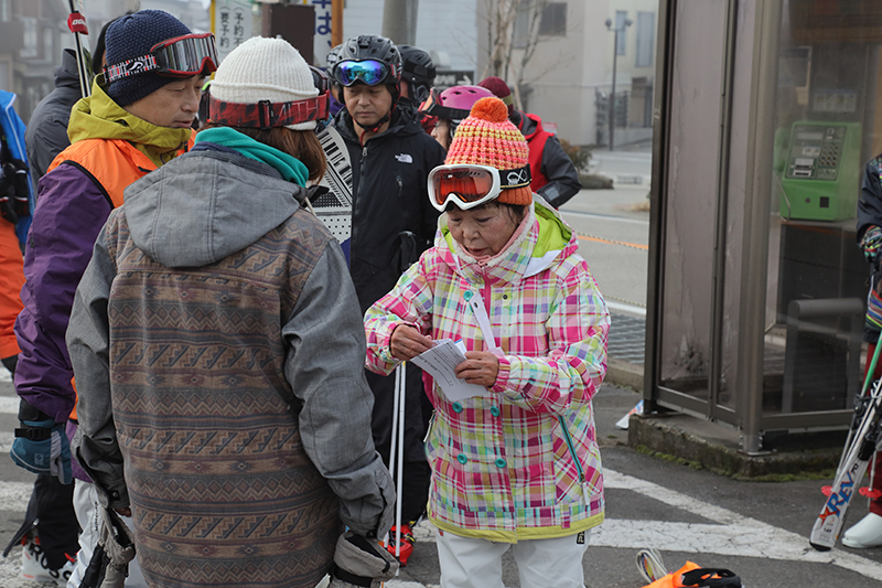 カラフルなスキーウェアに身を包んだ73才添乗員女性とツアー客