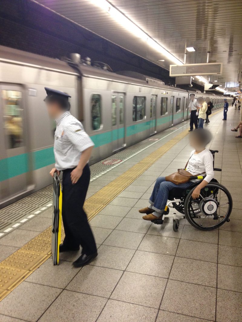 地下鉄の駅のホームで車椅子に乗る女性と駅員