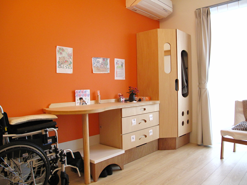 オレンジ色の壁の特養の居室