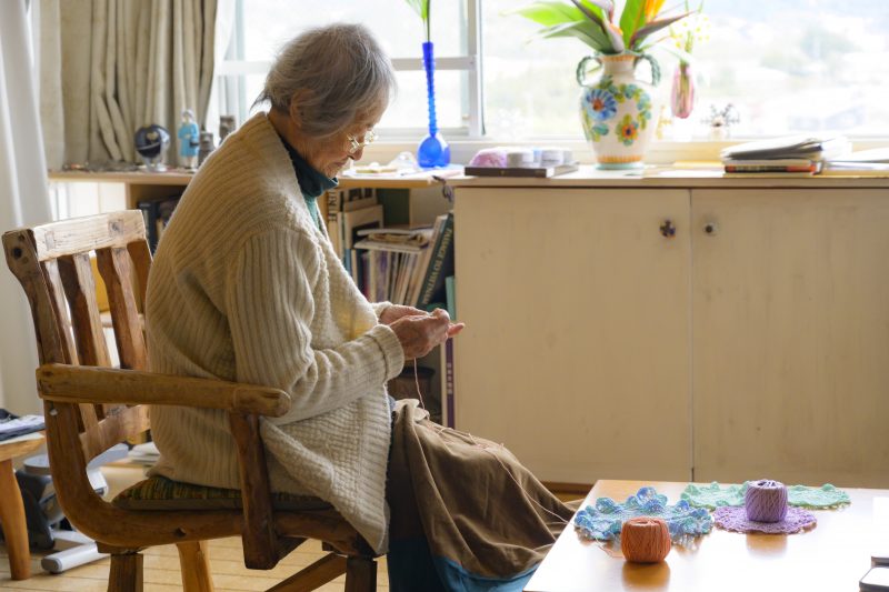 カラフルな糸を使って編み物をする高齢の女性
