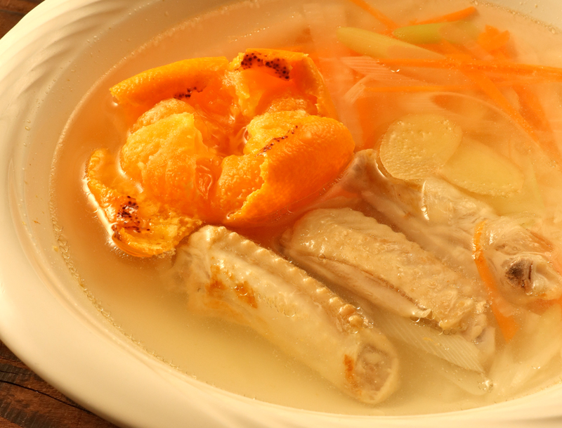 鶏手羽中とみかんのスープが皿に盛りつけられている