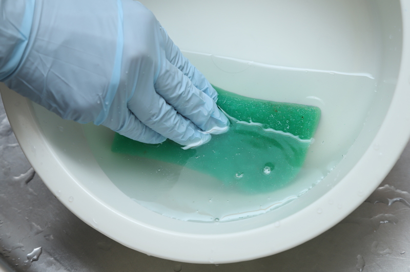 洗面器に入れた次亜塩素酸ナトリウム液にスポンジを浸している画像