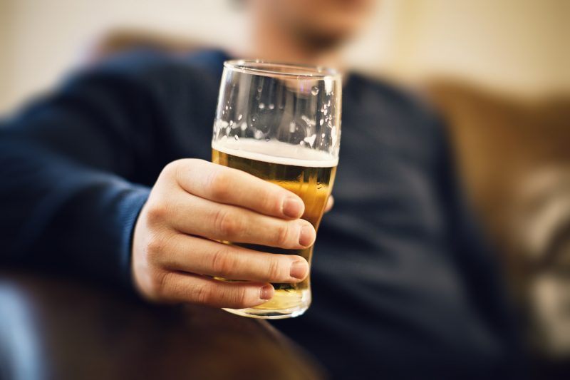 ビール片手にソファに座っている男性の画像
