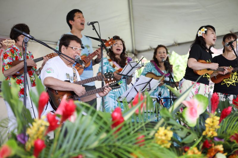 ハワイのイベントで大勢の人と一緒にウクレレを弾く高木ブーさん