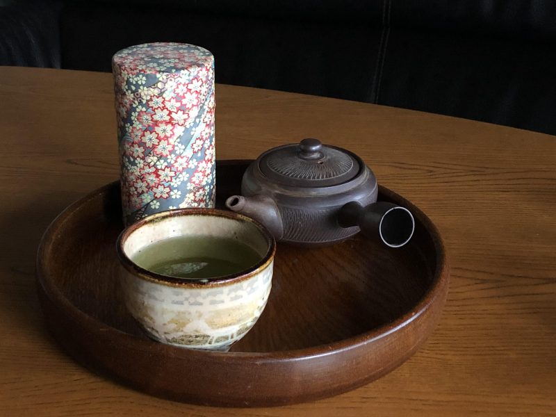 急須、茶筒、お茶の入った湯飲みがお盆に載っている