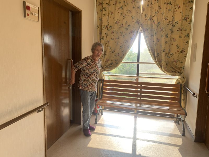 施設の部屋の入口に立つ飯田裕子さんの母