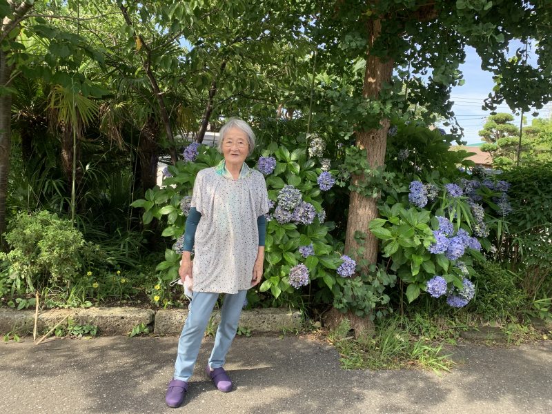 紫陽花の前に立つ飯田裕子さんの母