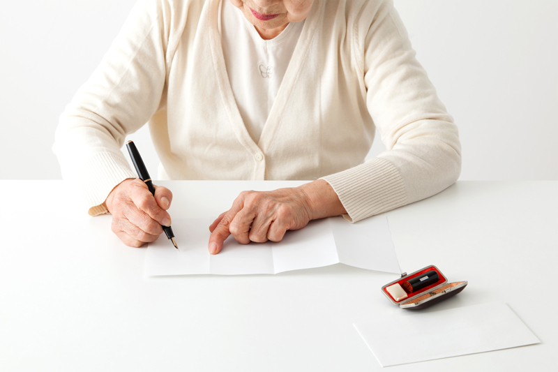 白い紙にペンで書き出そうとしているシニア女性