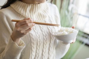 Woman holding white rice and chopsticks in a bowl