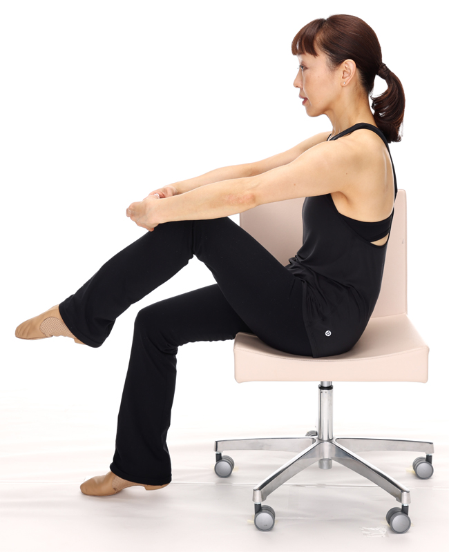 チェアバレエ　ひざ曲げの注意事項　両腕は下ろしたときに、ひざを抱えるようなイメージでポーズをとる。背中は後ろに引っ張られるよう、やや丸める。インナーマッスルである大腰筋や腹筋を鍛えることで、正しい姿勢や歩行能力の維持を目指そう。 