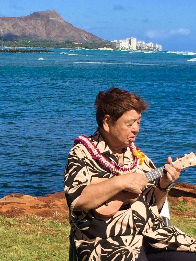 ハワイのダイヤモンドヘッドを背にウクレレを弾く高木ブー