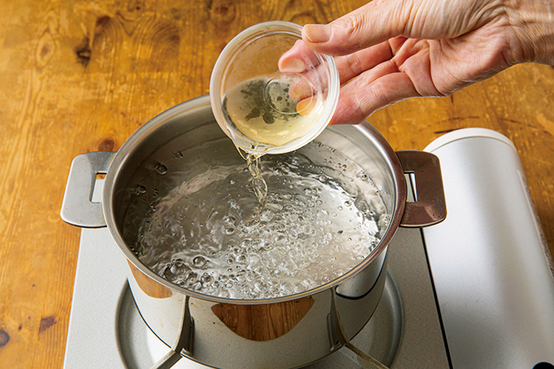 鍋で沸騰する湯に酢を入れている