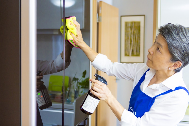 冷蔵庫の表面を掃除している女性