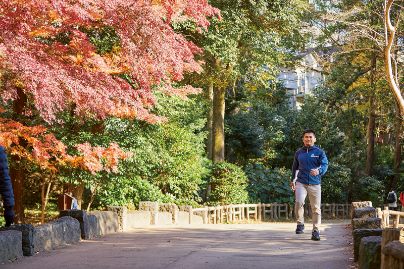 木々に囲まれた道を歩くフィジカルトレーナーの岩田勇樹さん