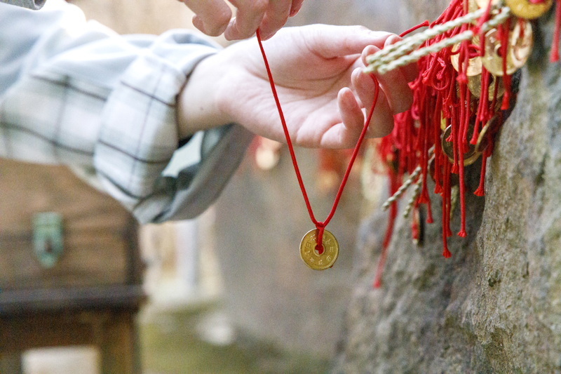 赤い糸のついた5円玉を境内の「縁結び石」に結ぶと恋愛運がアップ（葛原岡神社）