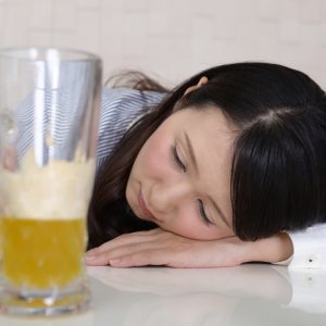 飲みすぎてテーブルに顔をつける女性