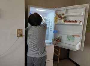 冷蔵庫の前に立つ工藤広伸さんのお母さん