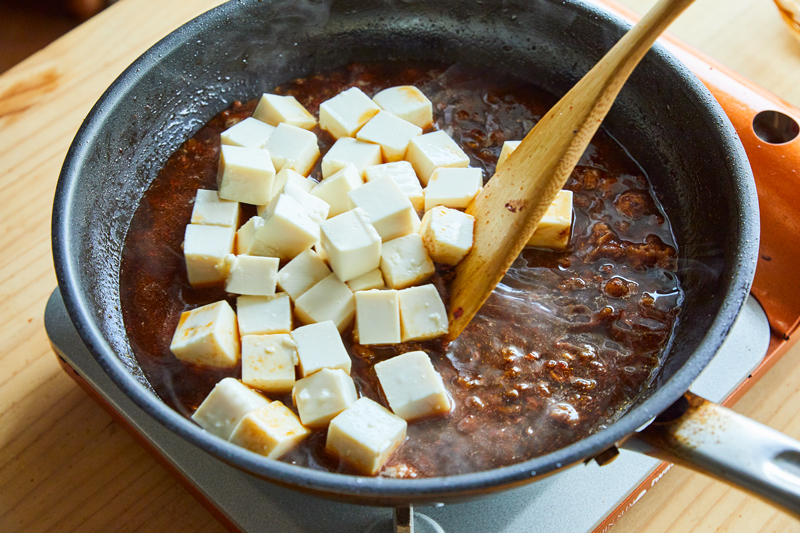 フライパンで調味料と豆腐を混ぜている写真