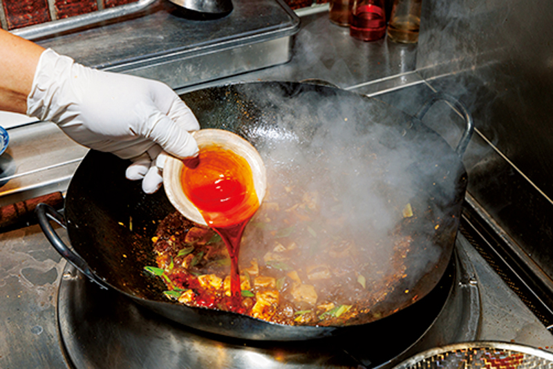 麻婆豆腐の鍋に油を注いでいる写真